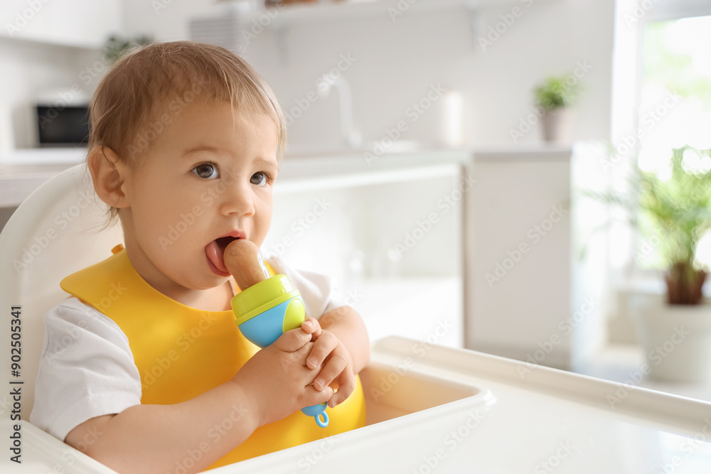 Cute little baby with bib and nibbler in kitchen, closeup Cute little baby with bib and nibbler in kitchen, closeup