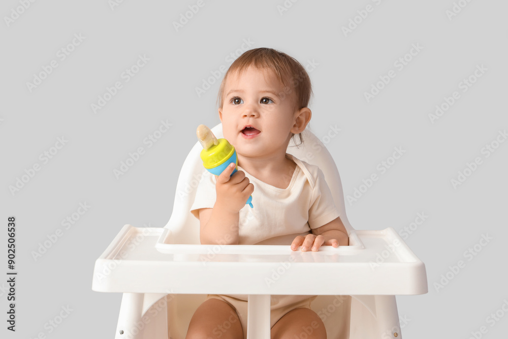 Cute little baby with nibbler in high chair on light background Cute little baby with nibbler in high chair on light background