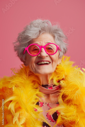 old eccentric lady smiling with grey hair and pink sunglasses wearing a big bright yellow feather boa, pastel pink background, party festive backdrop