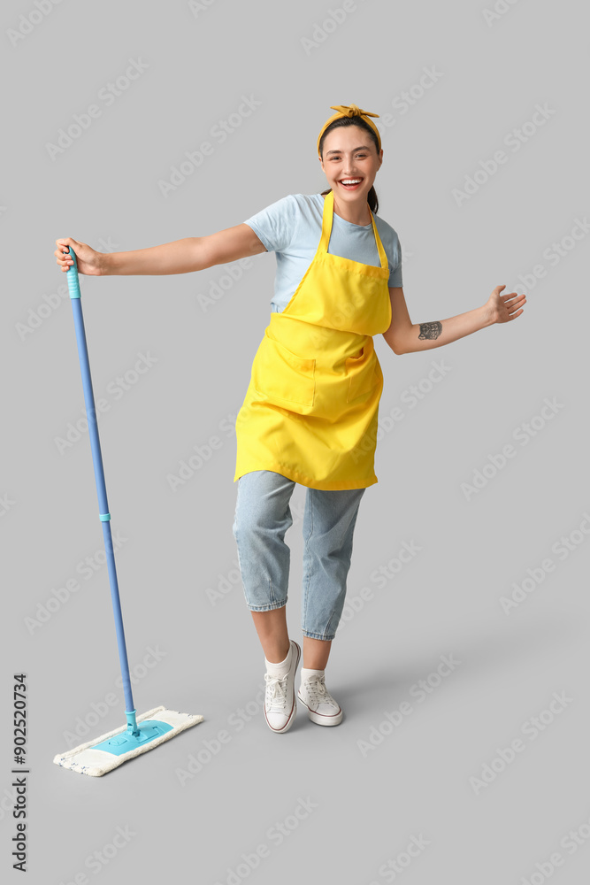 Beautiful young happy woman with mop on grey background Beautiful young happy woman with mop on grey background