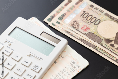 黒背景に電卓と預金通帳と一万円 photo