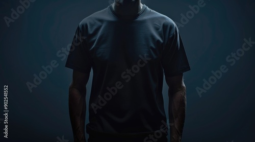 A man standing in front of a dark background, wearing a black t-shirt