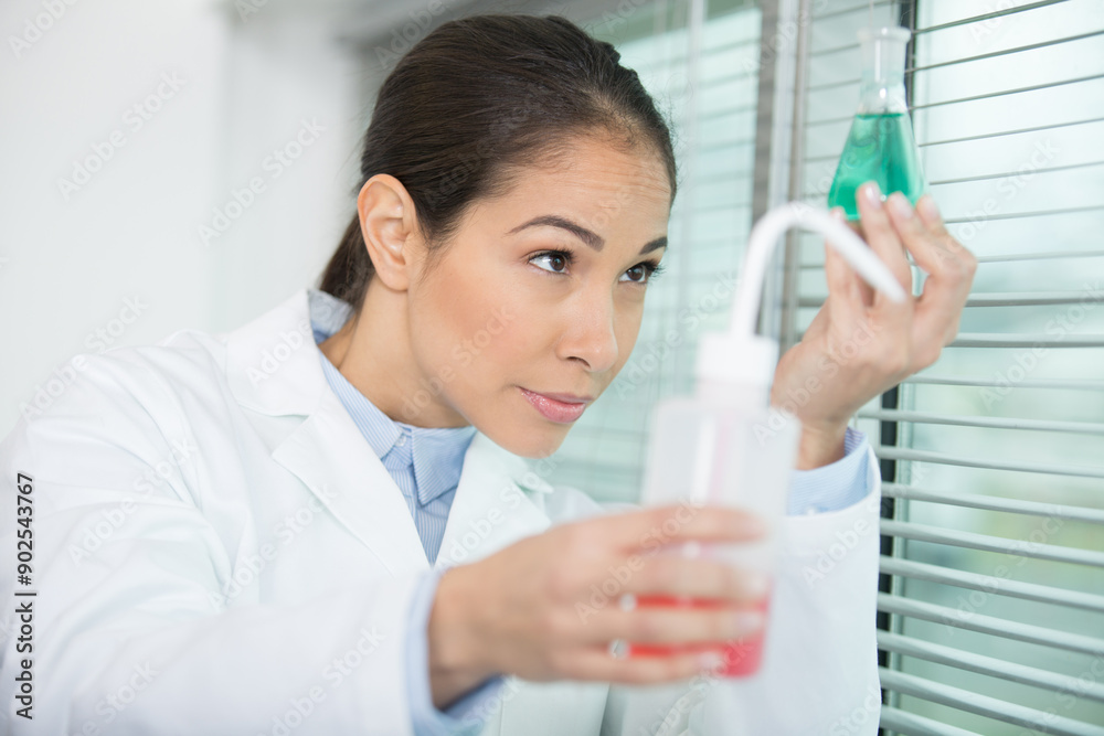 female scientist holding erlenmeyer flask up to the light female scientist holding erlenmeyer flask up to the light