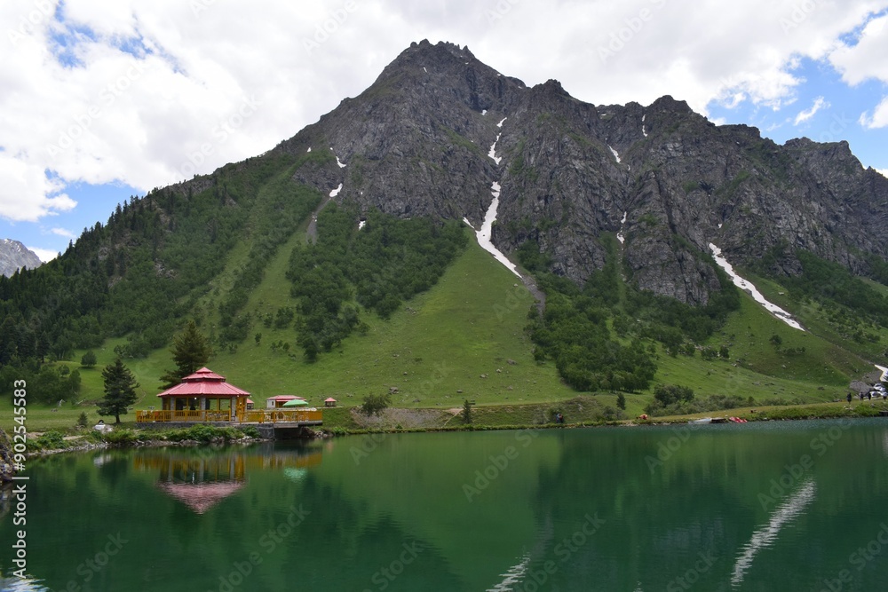 green alpine lake with hut and mountain at the background green alpine lake with hut and mountain at the background