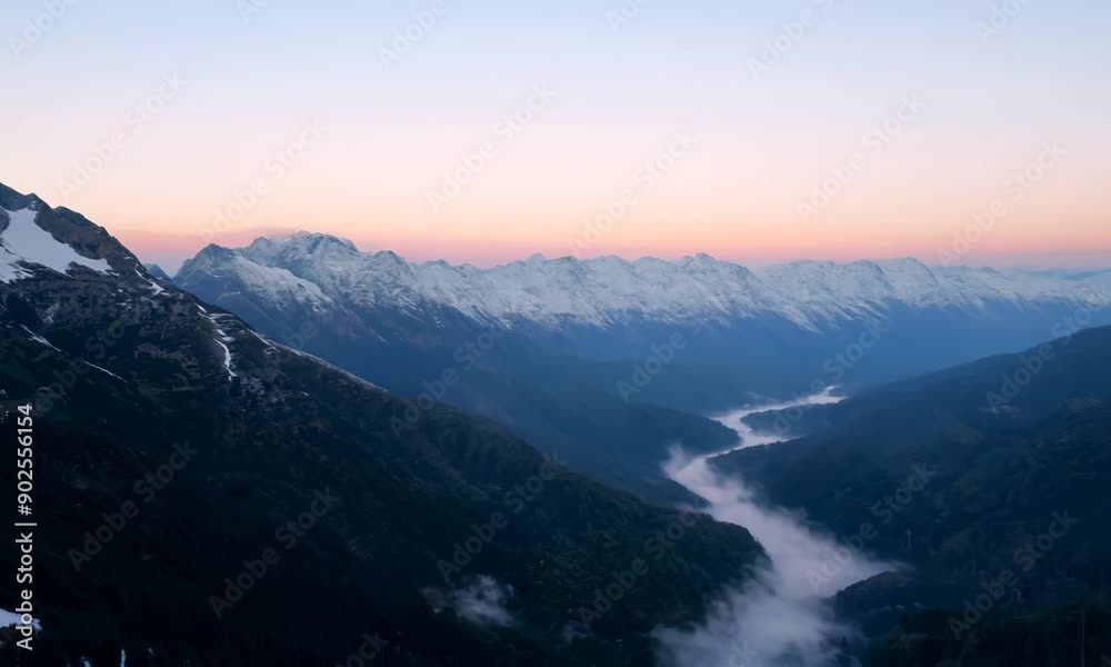 Majestic snow covered mountain peaks at sunrise, with a winding river and mist shrouded valley below, creating a serene and awe inspiring scene Majestic snow covered mountain peaks at sunrise, with a winding river and mist shrouded valley below, creating a serene and awe inspiring scene
