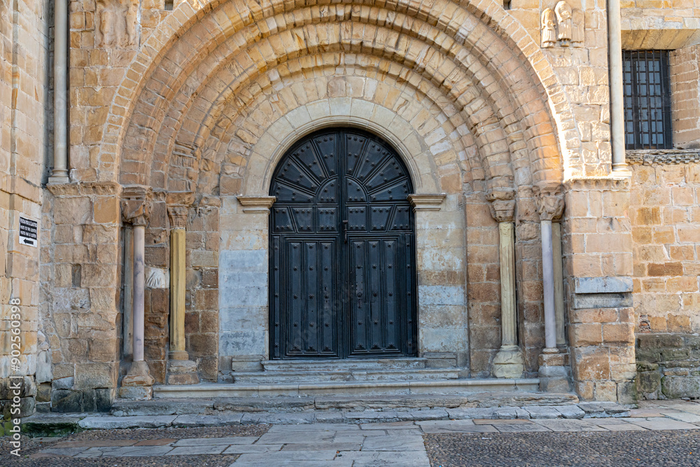 Fototapeta premium Close-up view of the architectural detail of the Collegiate Church of Santa Juliana in Santillana del Mar, Cantabria, Spain. The medieval stone structures are highlighted against a bright blue sky.