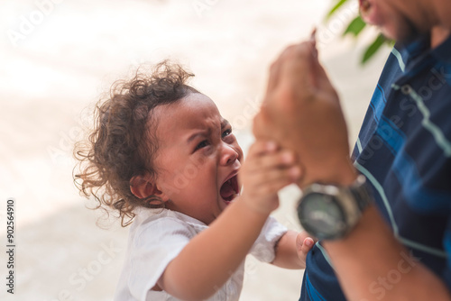 A young male toddler throws a tantrum and protests after his dirty toy is confiscated by his dad.