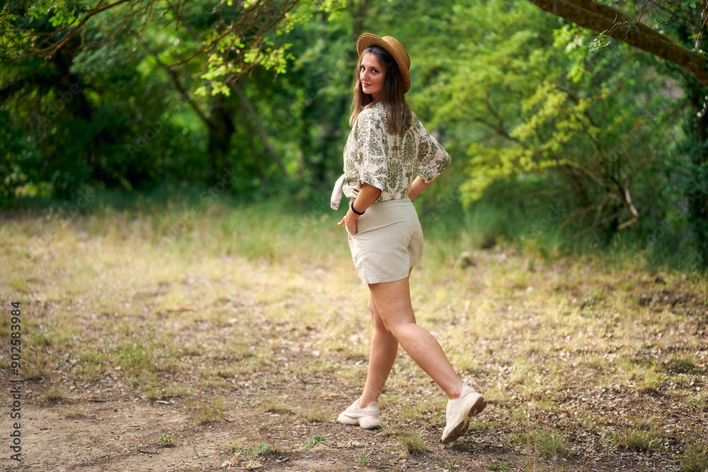 Young woman strolling leisurely through lush green forest Young woman strolling leisurely through lush green forest