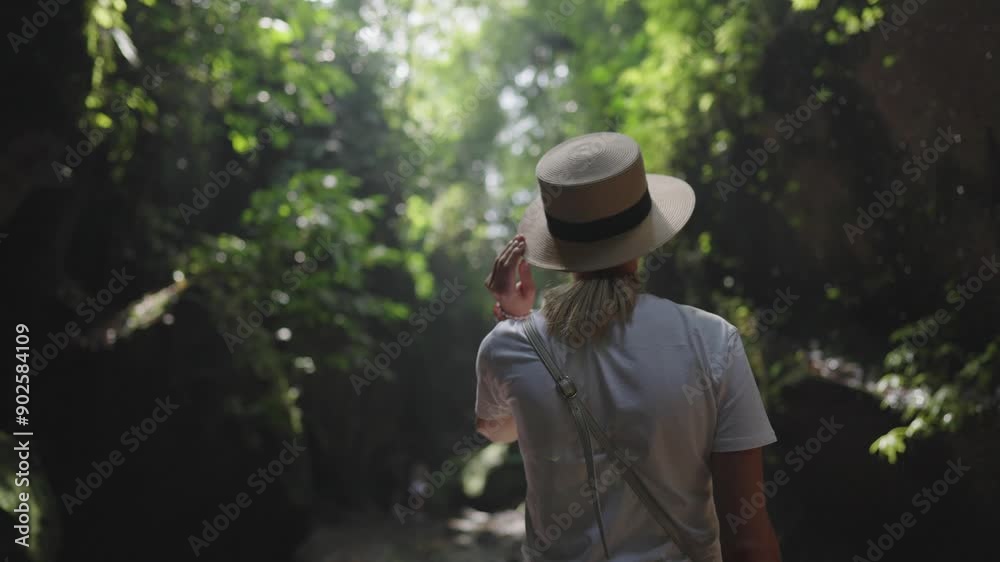 Young adult woman in beautiful rainforest in sunny summer day, back view. Slender lady enjoying beauty of tropical woodland and nature, water falling from up, slow motion, fairytale trip to jungle Young adult woman in beautiful rainforest in sunny summer day, back view. Slender lady enjoying beauty of tropical woodland and nature, water falling from up, slow motion, fairytale trip to jungle