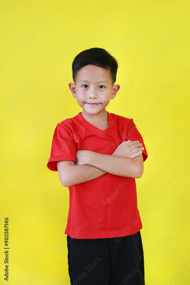 Smiling Asian boy child standing and cross arms over chest looking straight at camera isolated on yellow studio background. Smiling Asian boy child standing and cross arms over chest looking straight at camera isolated on yellow studio background.