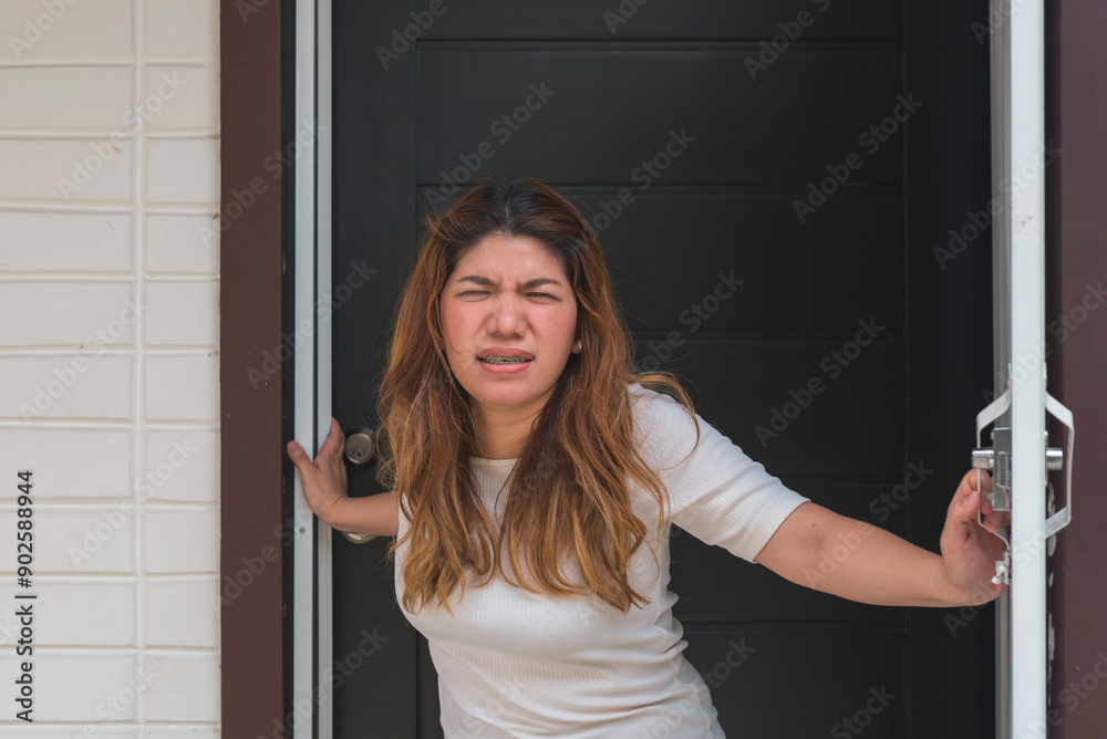 An asian woman standing right at the door annoyed at hecklers just outside her house. An asian woman standing right at the door annoyed at hecklers just outside her house.