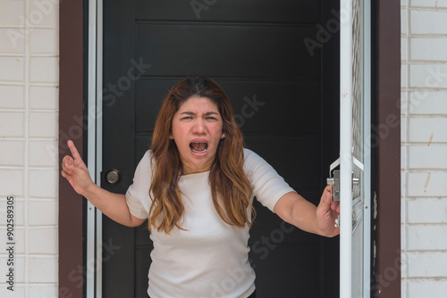 Valokuva An asian woman standing right at the door shouts at her neighbor to shut up and stop making noise