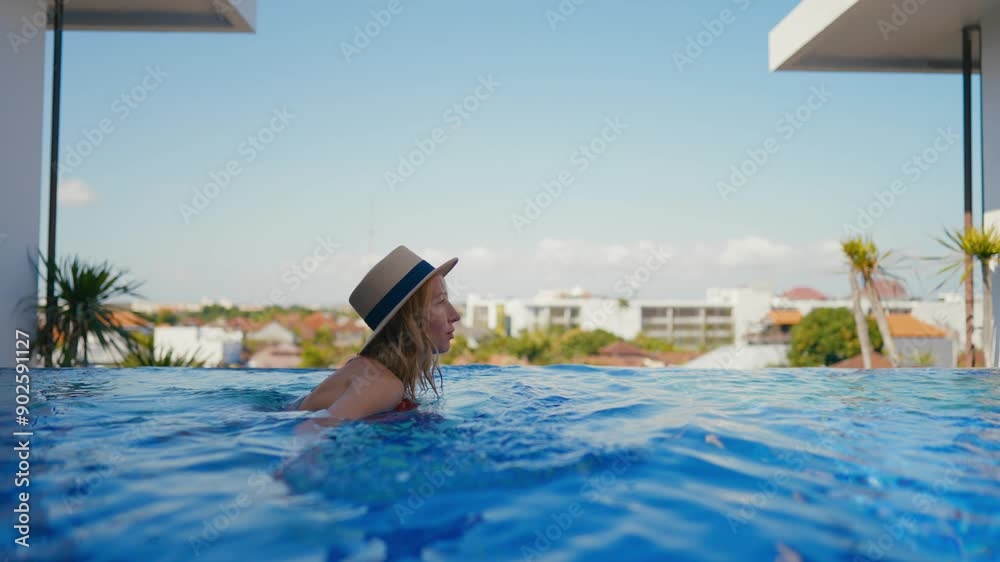 Woman swimming in beautiful endless pool in luxury apartment with city view. Attractive female tourist relaxing in resort hotel, slow motion, enjoy solitude in cool water, refreshing in hot summer day