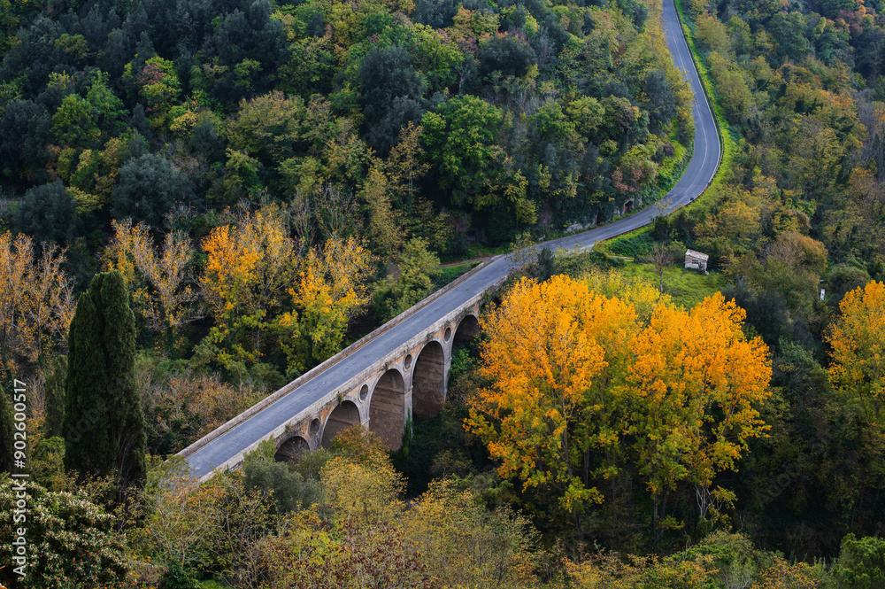 The picturesque authentic Italian landscape in Tuscany, Italy. Arched bridge and road in a autumn forest. The picturesque authentic Italian landscape in Tuscany, Italy. Arched bridge and road in a autumn forest.