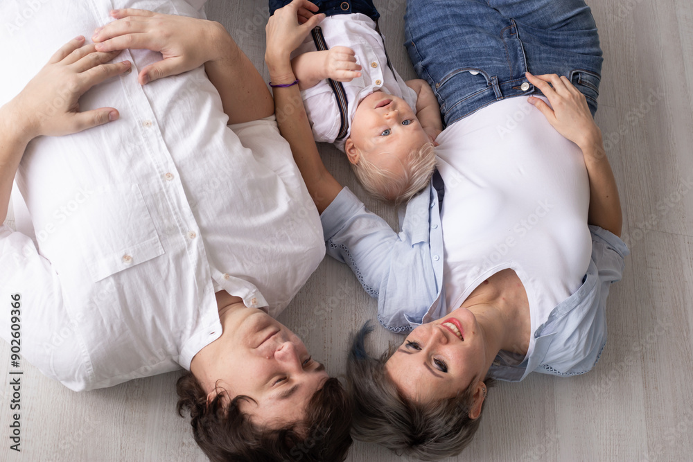 Happy family. Mother, father and their son baby boy having good time at home near colorful balloons on first baby birthday
