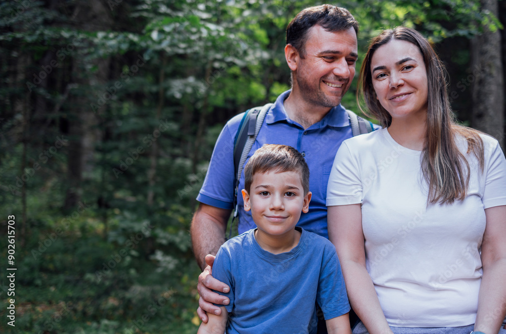 A close-up portrait of a happy family in the forest. A young married couple with their son are walking in the woods. Tourists enjoy nature and travel. A close-up portrait of a happy family in the forest. A young married couple with their son are walking in the woods. Tourists enjoy nature and travel.
