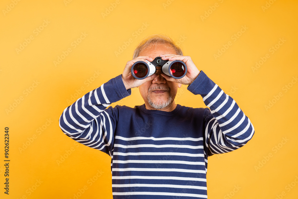 Portrait Asian smiling old man looking camera through binoculars studio shot isolated yellow background, senior man pensioner feeling surprised using binocular Portrait Asian smiling old man looking camera through binoculars studio shot isolated yellow background, senior man pensioner feeling surprised using binocular