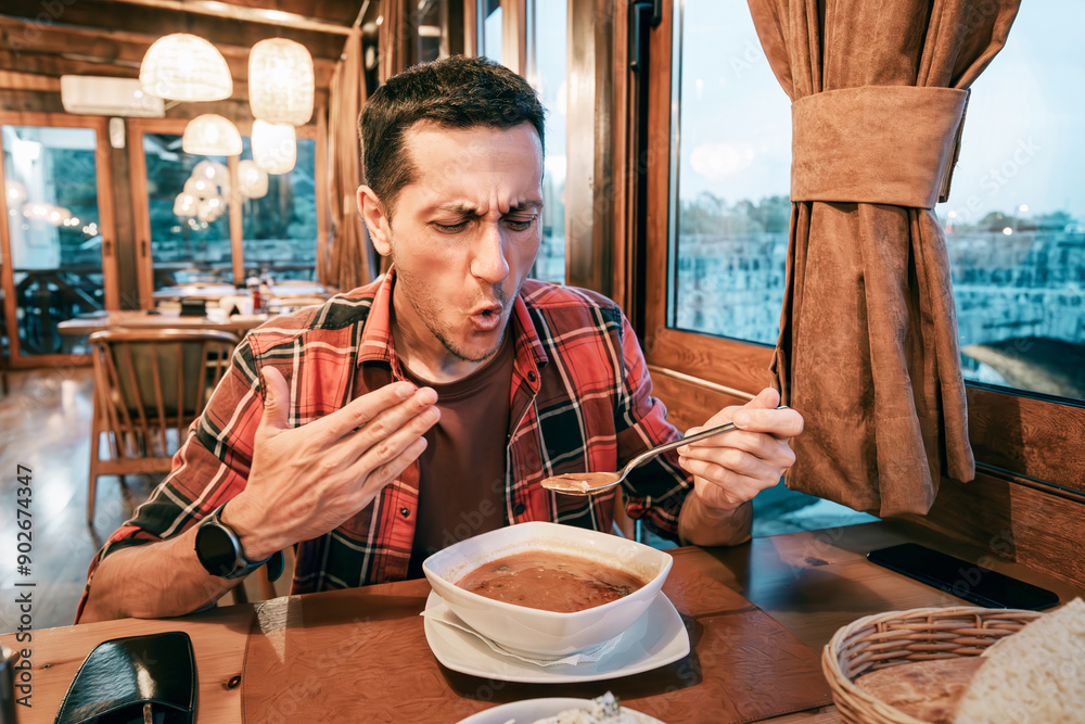 A man holding a bowl of tasty and spicy soup, enjoying a satisfying lunch.