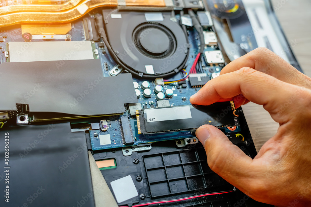 Fototapeta premium Laptop repair engineer PC computer and motherboard install random access memory ram ssd in computer lab top. The master installs the disk in his hands