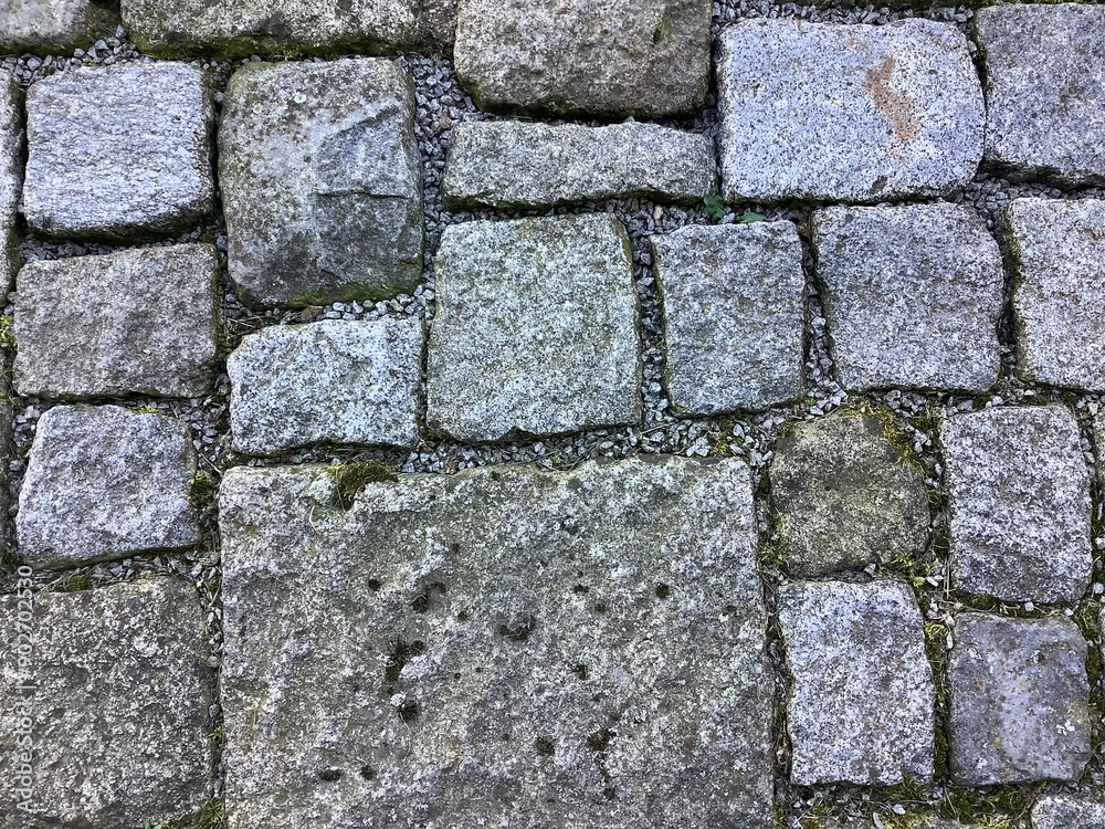 Grafische Elemente durch verschieden große Pflastersteine aus Granit auf einem Gehweg Grafische Elemente durch verschieden große Pflastersteine aus Granit auf einem Gehweg