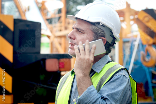 Quadro em tela Senior worker engineer foreman with safety vest and helmet talking on mobile phone while working at construction site