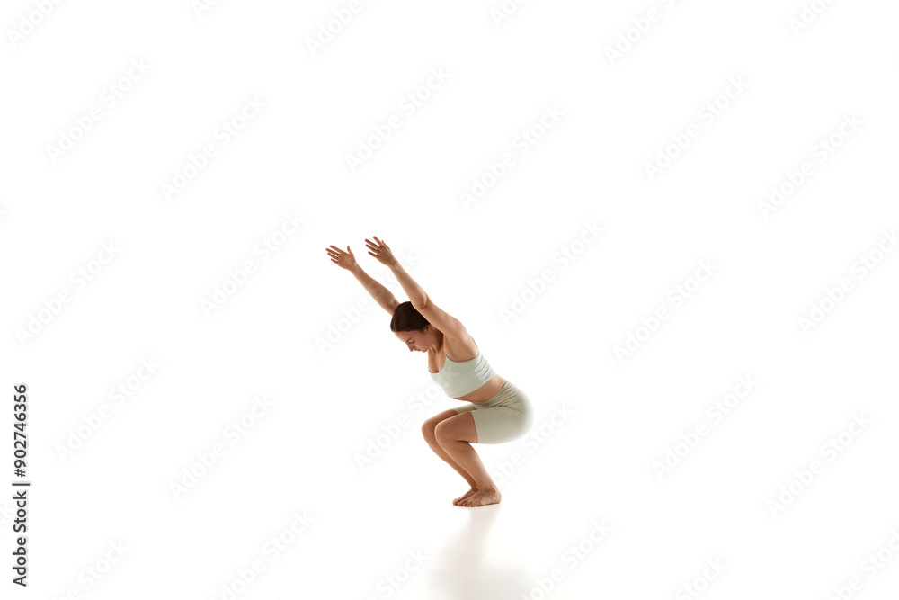 Dynamic photo of woman in athletic wear performs chair pose, bending her knees and against white studio background. Yoga. Concept of beauty, mindfulness and balance, mental health, concentration. Ad Dynamic photo of woman in athletic wear performs chair pose, bending her knees and against white studio background. Yoga. Concept of beauty, mindfulness and balance, mental health, concentration. Ad