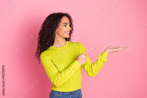 Portrait photo of youngster indian girl in green pullover demonstrate fresh product information isolated on pink color background