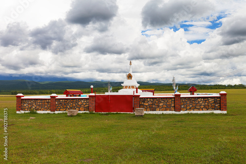 View of Buddhist Stupa of enlightenment against the background of blue sky with cumulus clouds on summer day. Siberia. Baikal region. Buryatia. Tunka  foothill valley. Natural reserve park photo