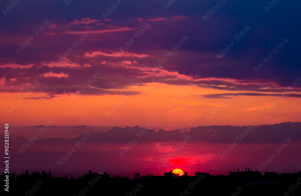 Sun at Sunset Almost Disappears Behind the Silhouettes of Buildings Sun at Sunset Almost Disappears Behind the Silhouettes of Buildings