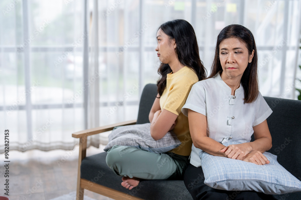 Two women are sitting on a couch, one of them is upset Two women are sitting on a couch, one of them is upset