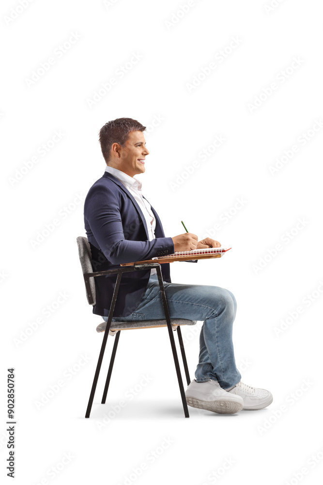 Man sitting in a school chair and writing Man sitting in a school chair and writing