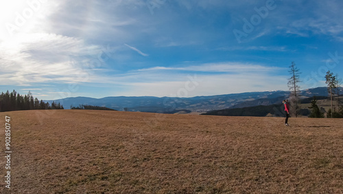 Woman on alpine meadow in West Styrian highland in Voitsberg, Styria, Austria. Hiking in remote landscape of soft hills and forest in spring. Scenic view of idyllic mountains of Lavanttal Alps photo