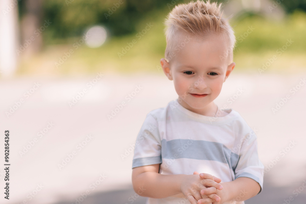 A fair-haired boy on a blurred summer background makes different emotional faces. A fair-haired boy on a blurred summer background makes different emotional faces.