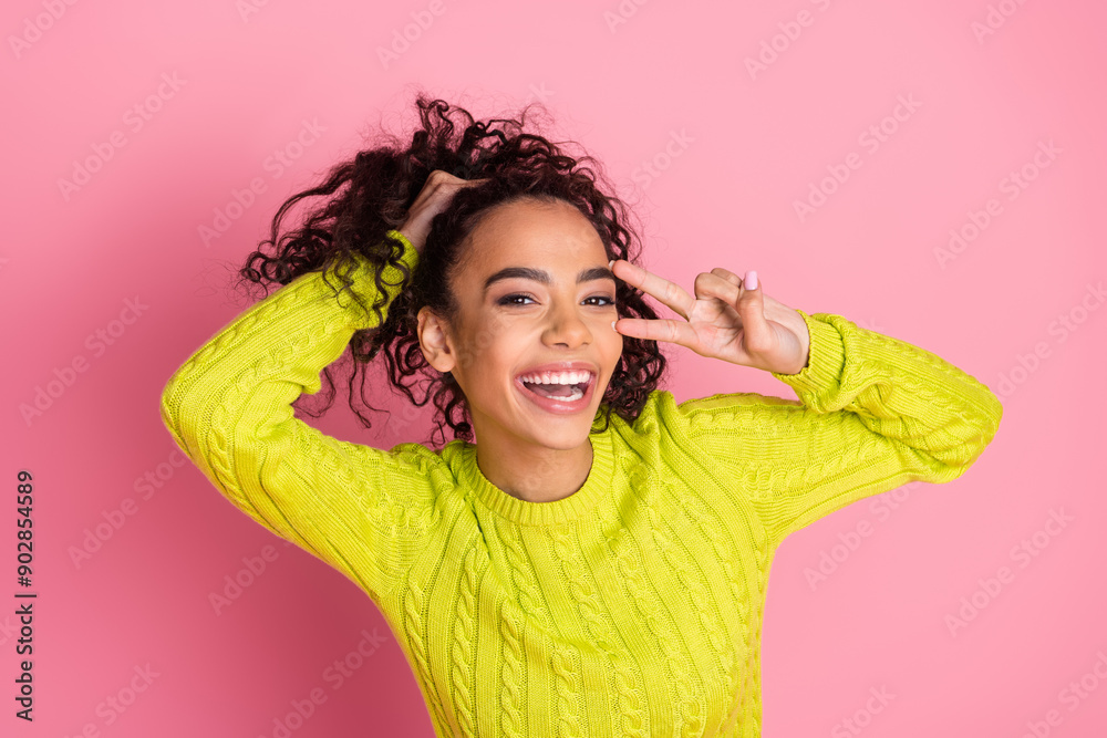 Portrait photo of youth funky teenager girl wearing green knitted sweater showing v sign over face isolated on pink color background Portrait photo of youth funky teenager girl wearing green knitted sweater showing v sign over face isolated on pink color background