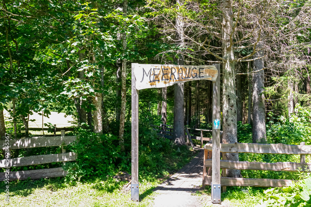 Wooden sign indicating the entrance of the alpine pond Meerauge in Boden Valley (Bodental) in Karawanks mountain range in Austria. Turquoise colored pond Austrian Alps. Direction mark Wooden sign indicating the entrance of the alpine pond Meerauge in Boden Valley (Bodental) in Karawanks mountain range in Austria. Turquoise colored pond Austrian Alps. Direction mark