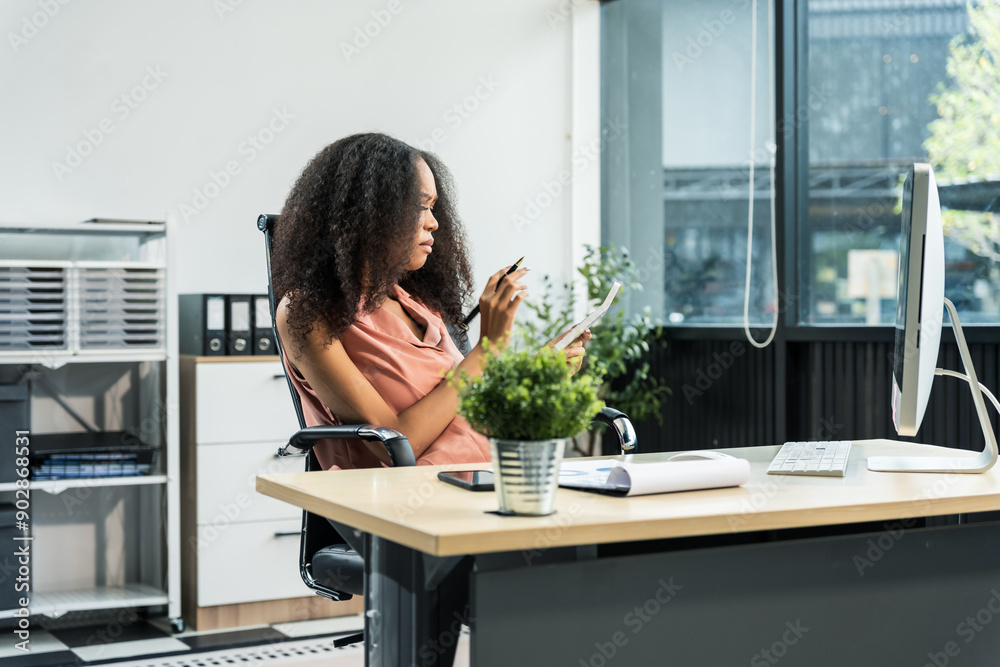 An African American woman with an afro works at a wooden desk in an office, focusing on business finance for startup. She manages market research, scalability, and interacts with angel investors. An African American woman with an afro works at a wooden desk in an office, focusing on business finance for startup. She manages market research, scalability, and interacts with angel investors.