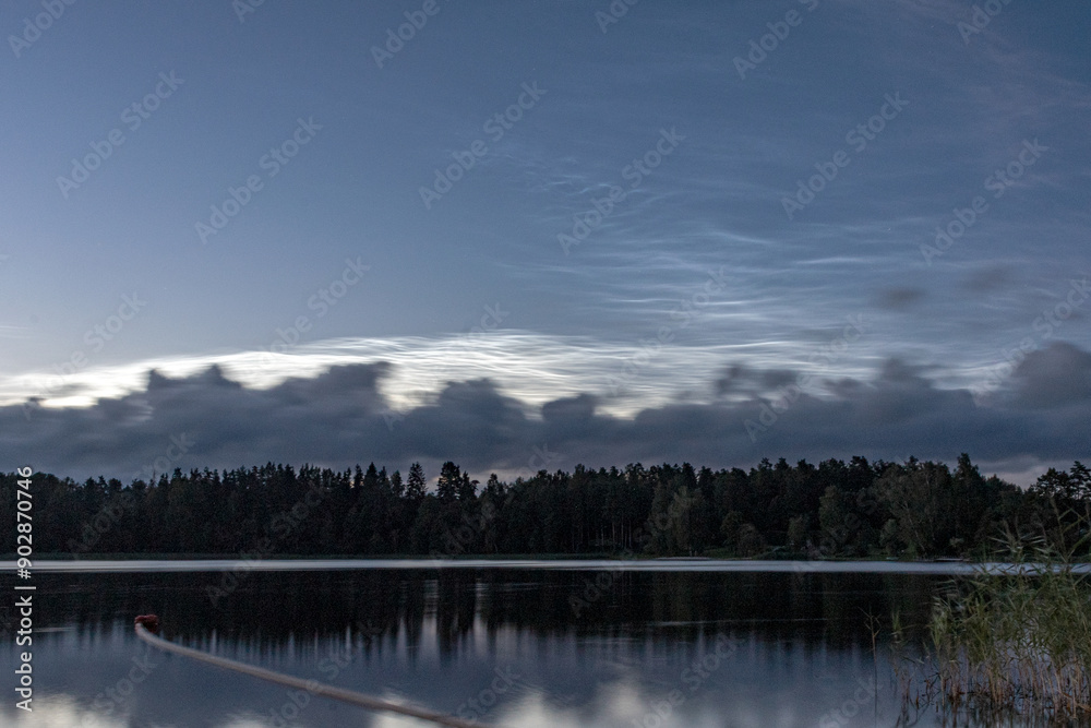 Fototapeta premium charming night landscape with silver clouds, silver clouds over the lake, dark forest silhouette in the background, mesospheric clouds