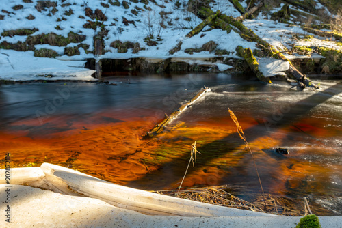 small, wild river in spring, calm river flow, ice and snow on the banks of the river, Strikupe, Vaidava, Latvia photo