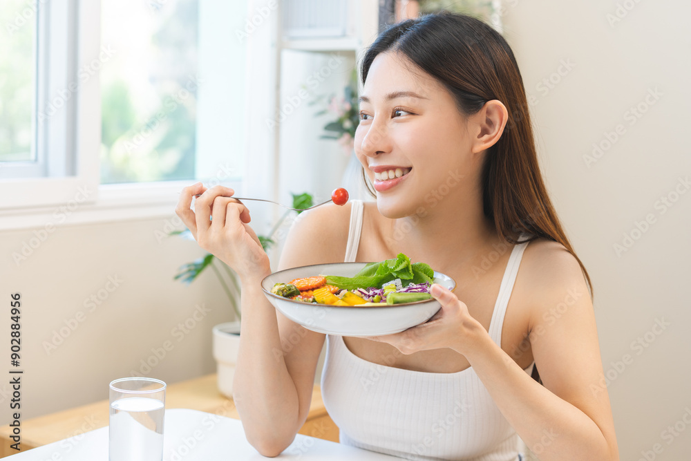 Diet concept, happy asian young woman hand use a fork to prick tomato, fresh vegetable or green salad, eat nutrition food on table at home, low fat to good body. Girl getting weight loss for healthy. Diet concept, happy asian young woman hand use a fork to prick tomato, fresh vegetable or green salad, eat nutrition food on table at home, low fat to good body. Girl getting weight loss for healthy.