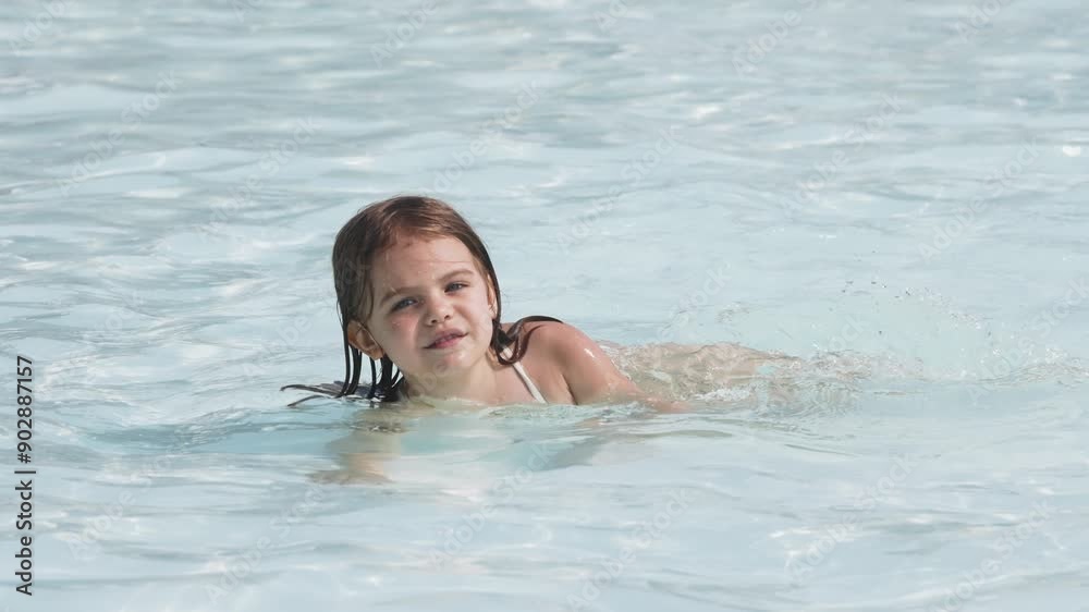 A girl happily splashes around in the pool, enjoying a summer day. Perfect for advertising related to children's activities, family events, and summer products. A girl happily splashes around in the pool, enjoying a summer day. Perfect for advertising related to children's activities, family events, and summer products.