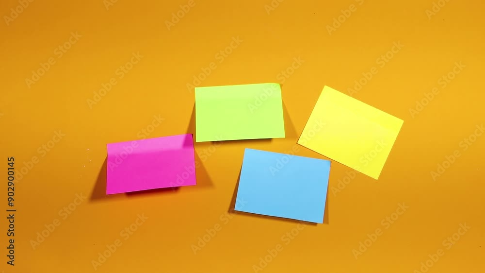 A woman hand sticks a colorful  pieces of paper for notes on a yellow surface