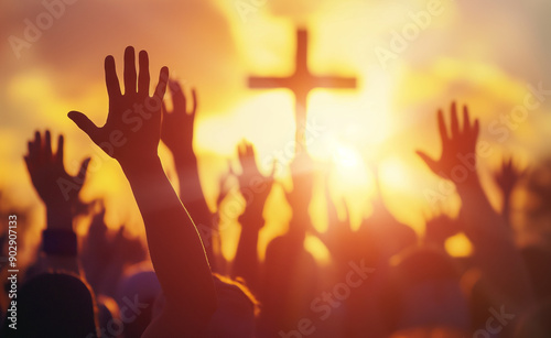 Hands raised in worship in front of a cross at sunset.