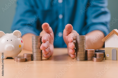 Divorce law and heritage separation concept. Hand separate saving money, financial, home loan, debt with piggy bank and wood house. Bank business investment. Man separate stack coin on table
