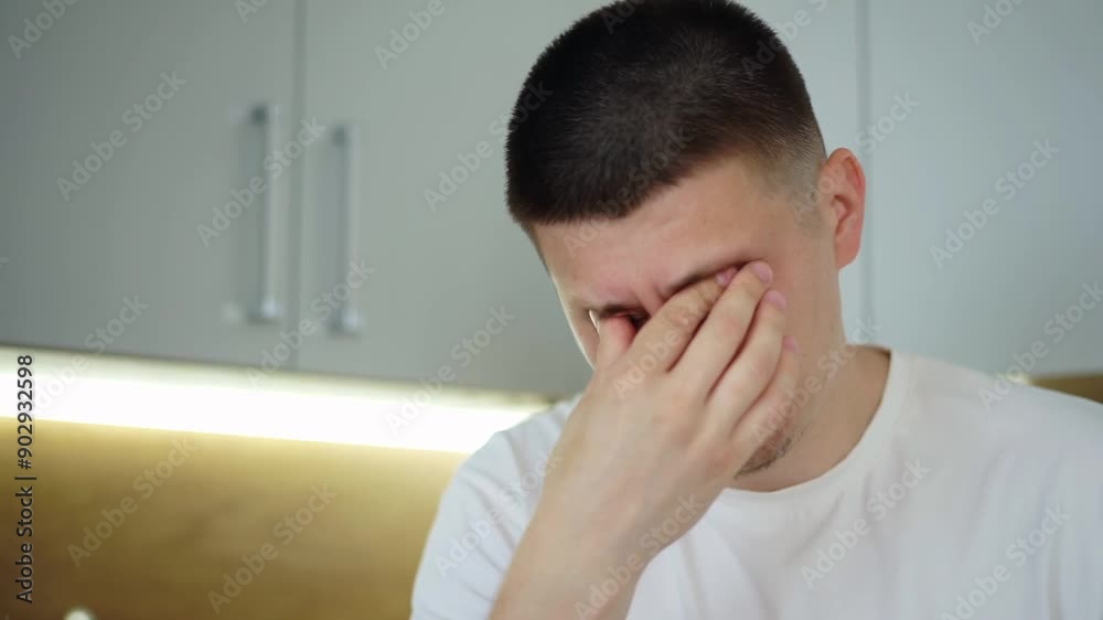 A sick young man sneezes into a tissue and blows his nose. A guy who has cold symptoms from flu and coronavirus. Covid 19 virus infection, flu and seasonal allergies concept. Close-up view A sick young man sneezes into a tissue and blows his nose. A guy who has cold symptoms from flu and coronavirus. Covid 19 virus infection, flu and seasonal allergies concept. Close-up view