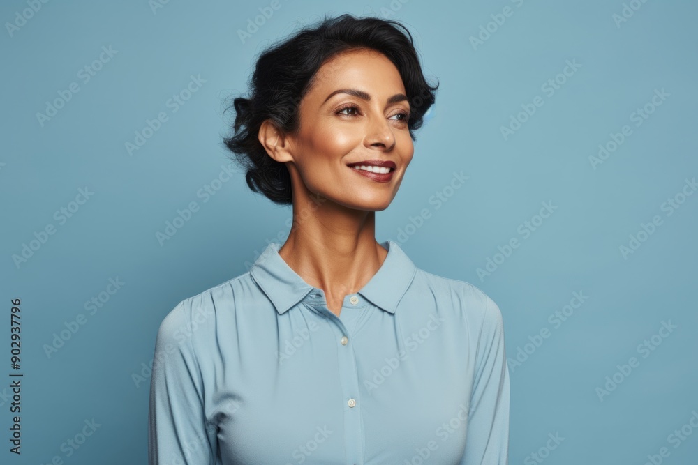 Portrait of a blissful indian woman in her 40s donning a classy polo shirt while standing against pastel blue background