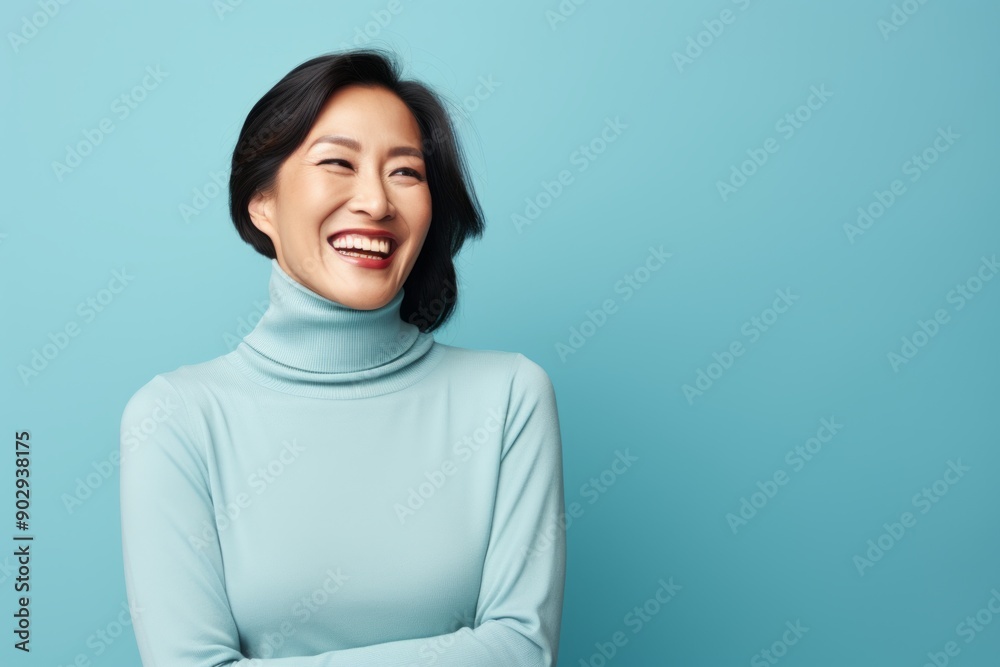 Portrait of a joyful asian woman in her 40s wearing a classic turtleneck sweater on pastel blue background Portrait of a joyful asian woman in her 40s wearing a classic turtleneck sweater on pastel blue background