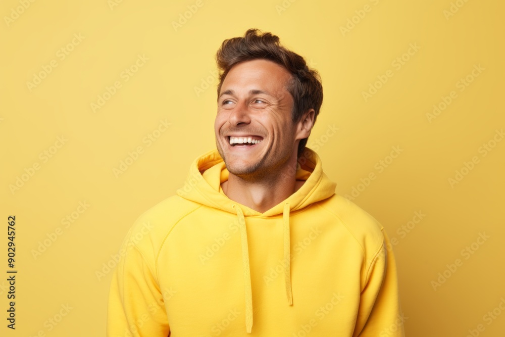 Portrait of a smiling man in his 30s wearing a thermal fleece pullover while standing against pastel yellow background Portrait of a smiling man in his 30s wearing a thermal fleece pullover while standing against pastel yellow background