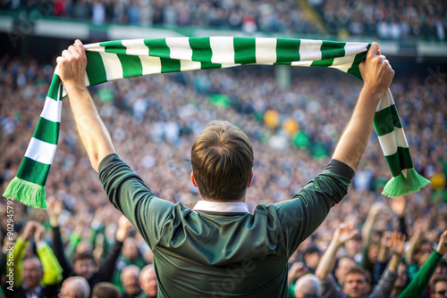 Back view of football soccer fan cheering his team with green and white scarf