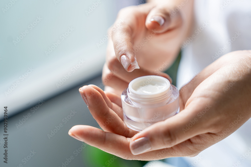 Partial view of woman holding jar with face cream Partial view of woman holding jar with face cream