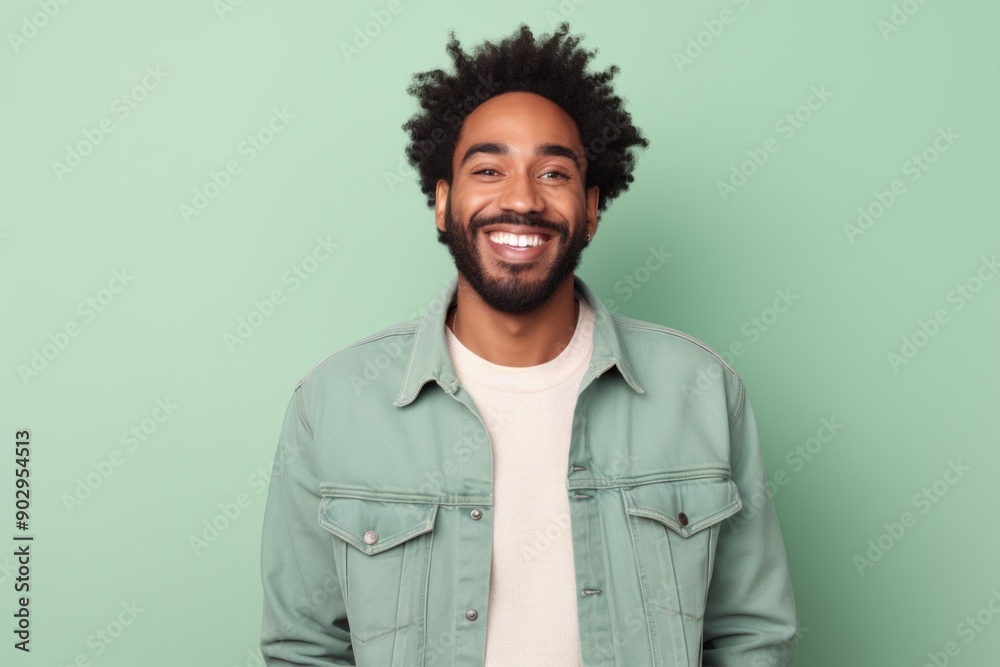 Portrait of a happy afro-american man in his 30s sporting a rugged denim jacket on pastel green background Portrait of a happy afro-american man in his 30s sporting a rugged denim jacket on pastel green background